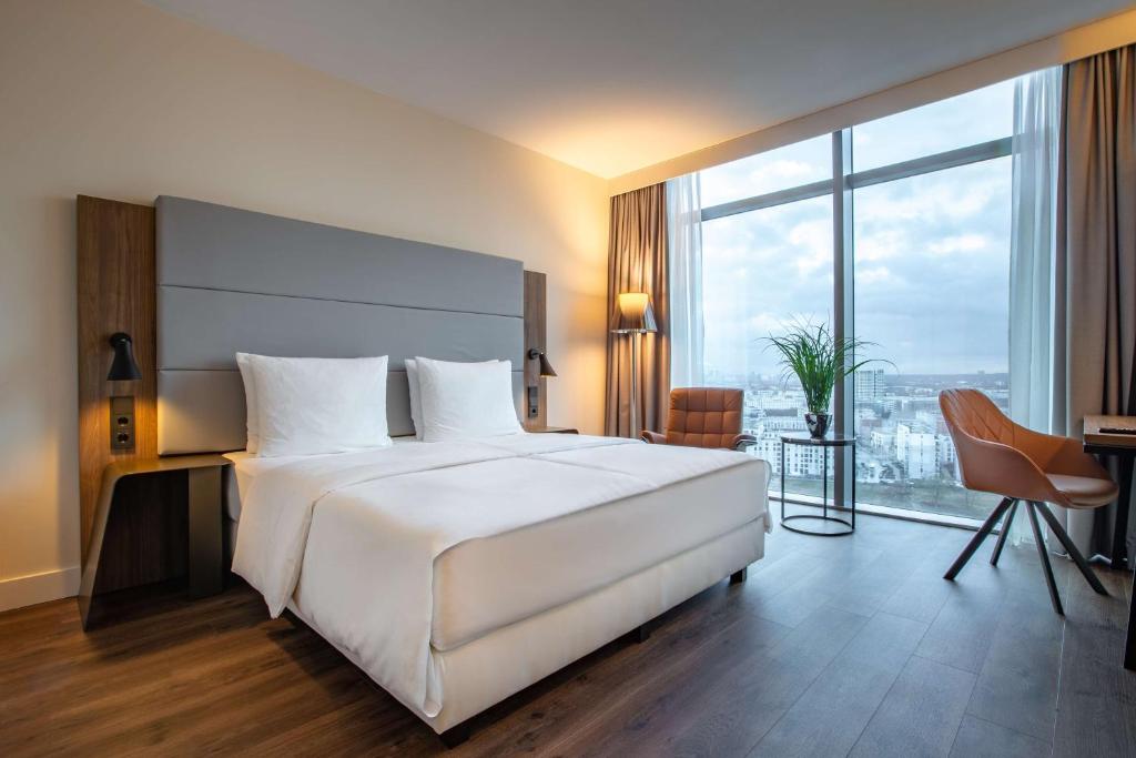 a bedroom with a large white bed and a large window at Radisson Blu Hotel Frankfurt in Frankfurt