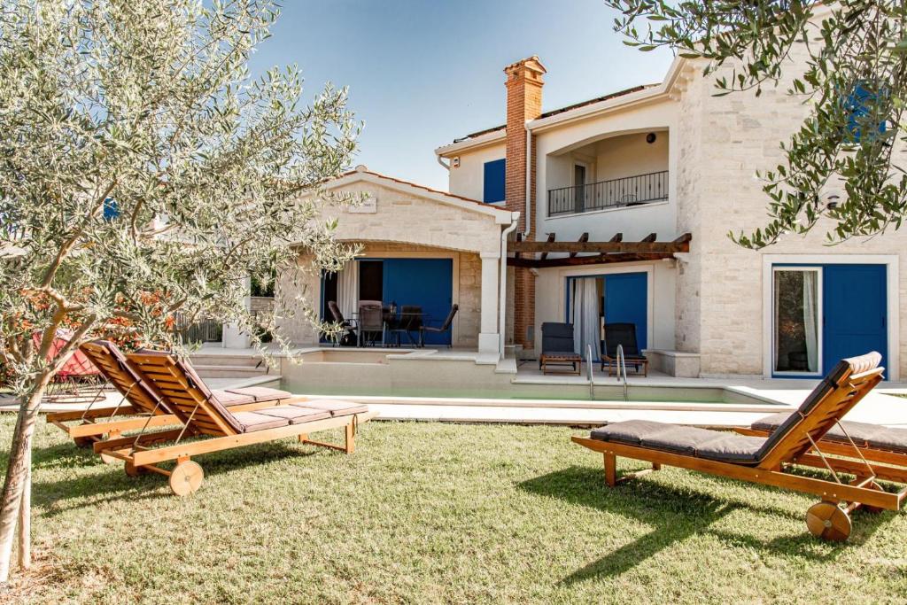 een achtertuin met twee ligstoelen en een huis bij Beautiful Villa Torre I with whirlpool in Tar in Frata