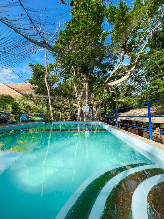 a swimming pool with blue water and trees at EL BOSQUE RESORT CORON in Coron