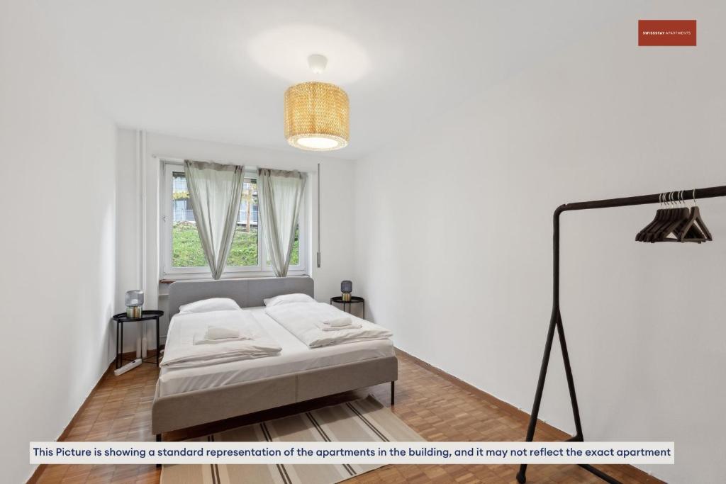 a white room with a bed and a window at 15-Min to Zurich Center: Cozy Apartment in Zurich