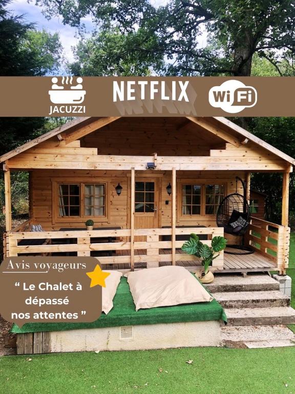 ein kleines Holzhaus mit einem Bett im Gras in der Unterkunft Le Chalet avec jacuzzi privatif in Nargis