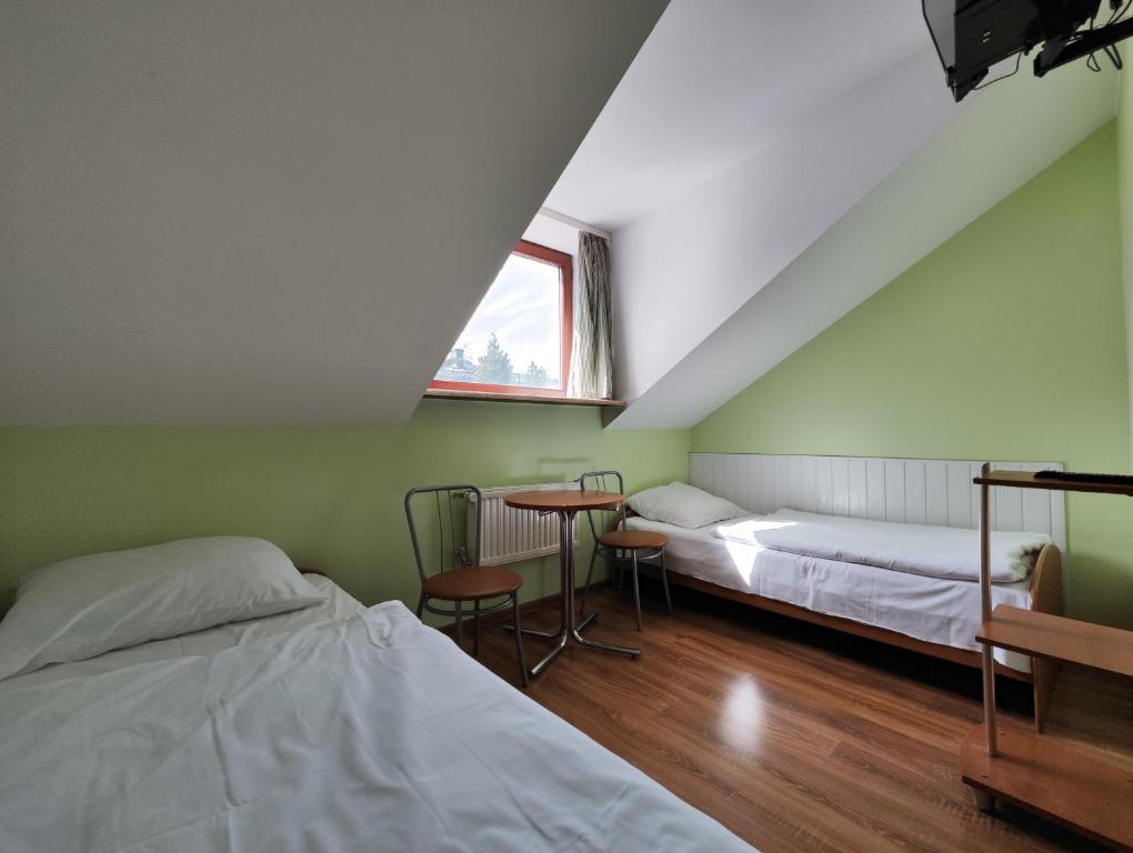 トゥシンにあるPokoje Gościnne Soniaのベッド2台、テーブル、窓が備わる客室です。