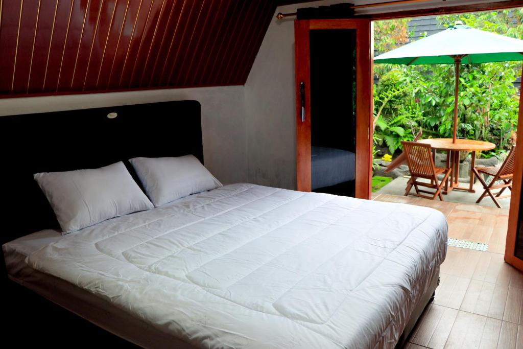 a bedroom with a bed and a patio with an umbrella at Goa Walet Cottage in Praya