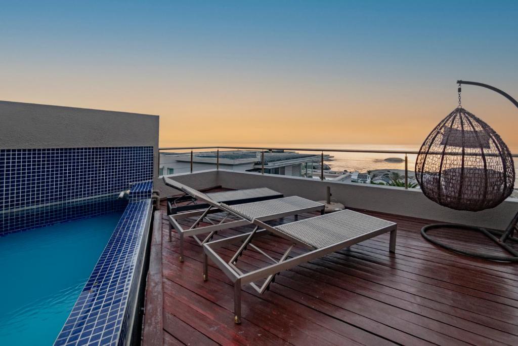a balcony with a pool and a chandelier at Stylish Penthouse with 180 degree Ocean Views! in Cape Town