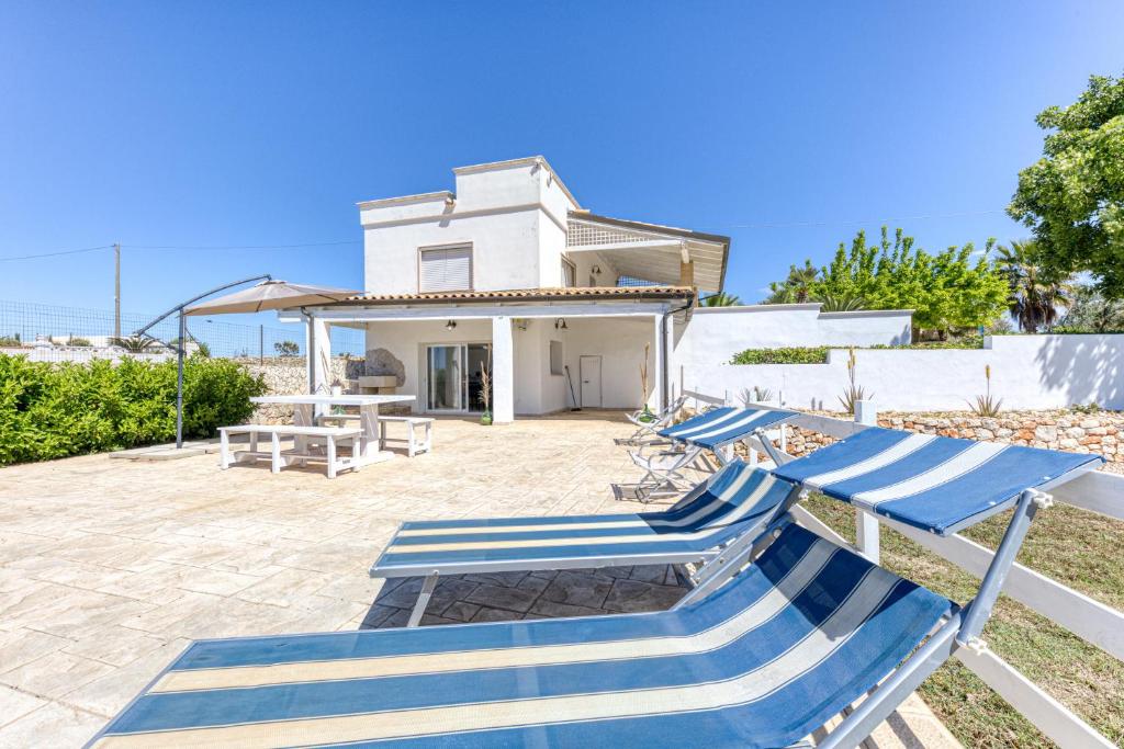 eine Terrasse mit blauen und weißen Stühlen und ein Haus in der Unterkunft Casa Gianna in Marina di Pescoluse