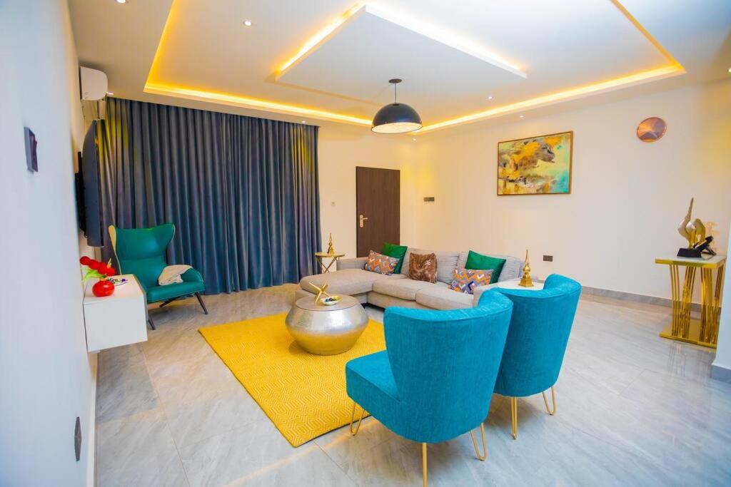 een woonkamer met blauwe stoelen en een bank bij The Pearl - Bountiful - 1st floor in Kumasi