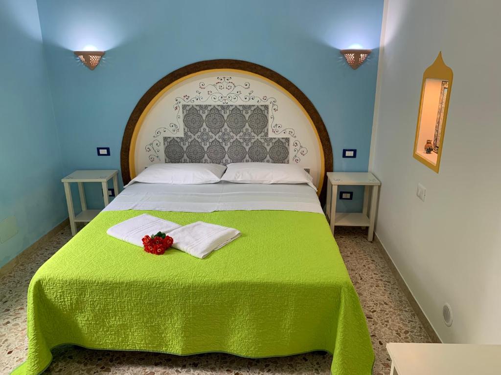 a bedroom with a large bed with a green blanket at Bed & Breakfast Sole Azzurro in Custonaci