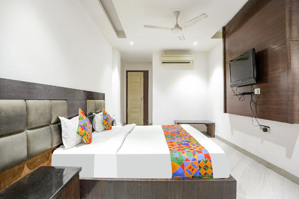 um quarto com uma cama branca e uma televisão em FabExpress Lotus Palace em Nova Deli