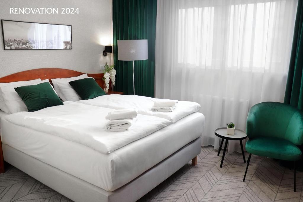 a bedroom with a white bed and a green chair at Hotel Polonia Centrum in Wrocław