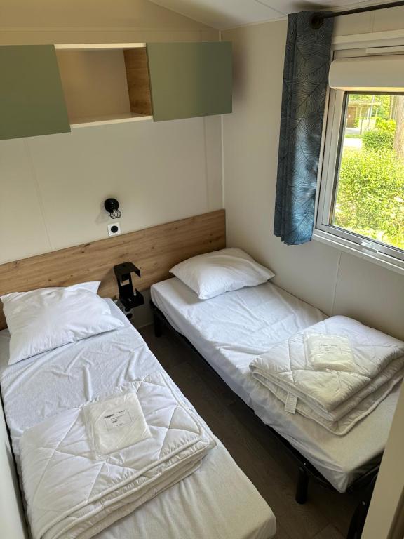two beds in a room with a window at Camping La sablière in Saint-Jans-Cappel