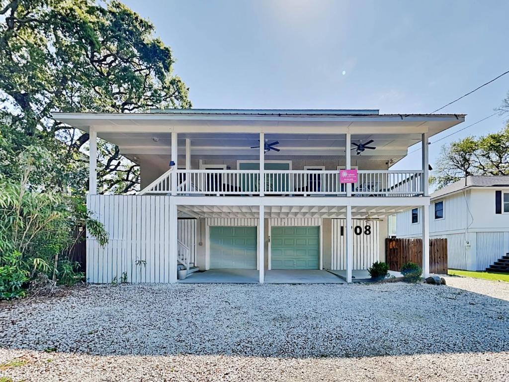 a white house with a deck on top of it at Boho Beach House in Tybee Island