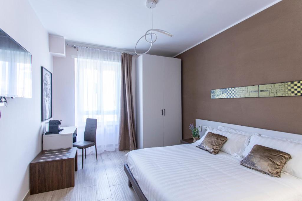 a bedroom with a white bed and a desk and a chair at MAMA GUEST HOUSE in Ciampino