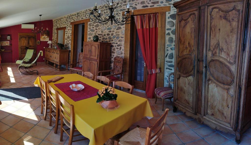 a dining room with a yellow table and chairs at Le Petit Caboulot en pleine nature in Vaumeilh