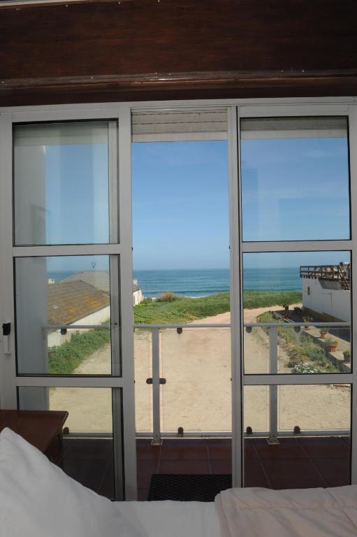 a bedroom with a view of the ocean seen through windows at Vivenda Sol E Mar in Baleal