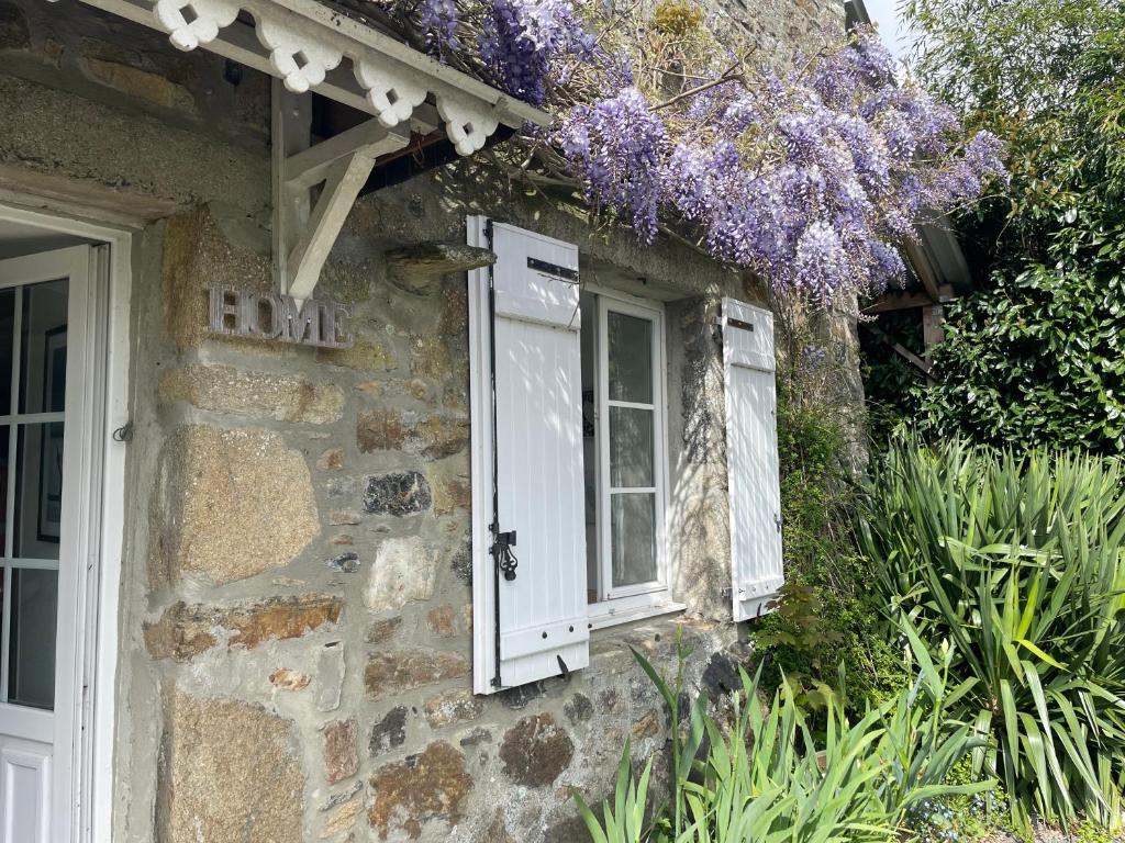 ein altes Steinhaus mit einem Fenster und lila Blumen in der Unterkunft Studio indépendant avec jardin privatif in Le Lorey