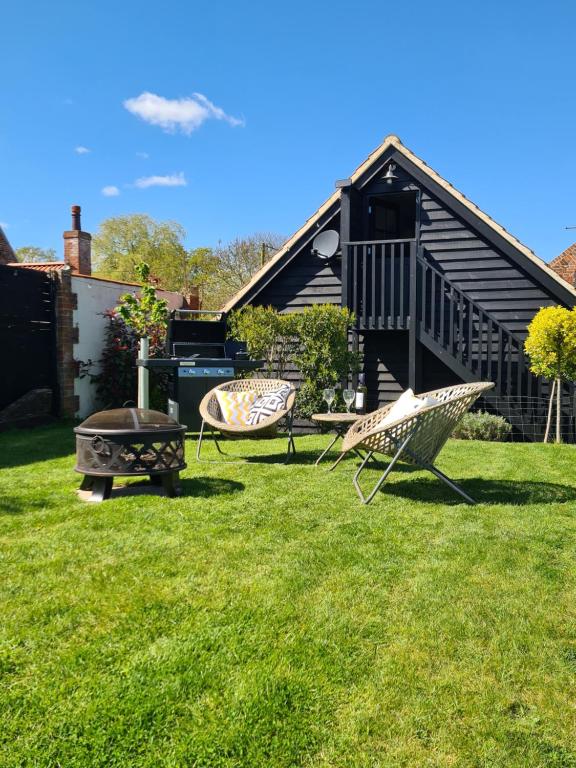 podwórze z dwoma krzesłami, grillem i domem w obiekcie The Cartshed, Coltishall, Norfolk w mieście Norwich