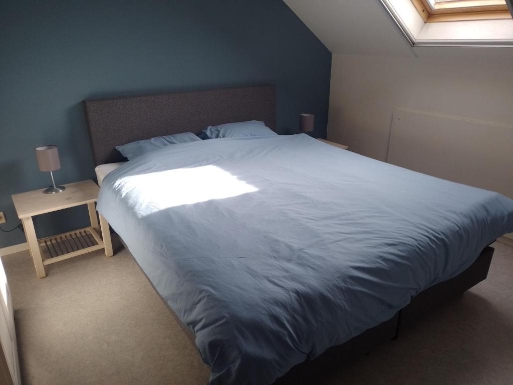 a bedroom with a large white bed with a window at Golfbreker in De Haan