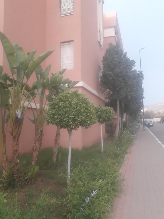 una fila de árboles junto a un edificio rosa en ديار الاطلس بني ملال المغرب, en Beni Mellal