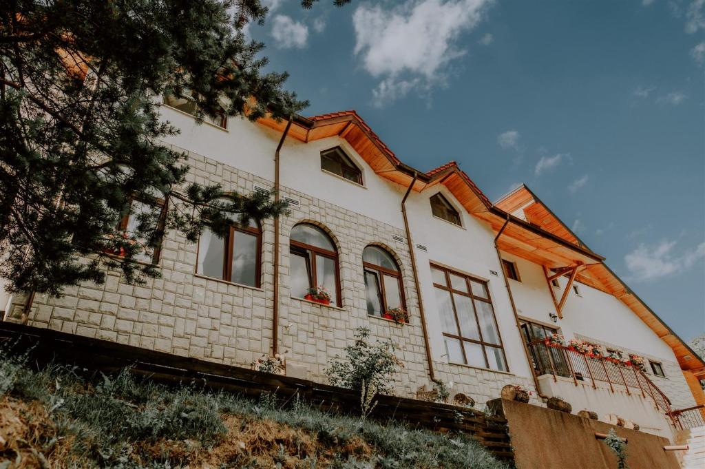 una casa de ladrillo blanco con ventanas en una colina en Pensiunea Poiana Verde, en Slănic-Moldova