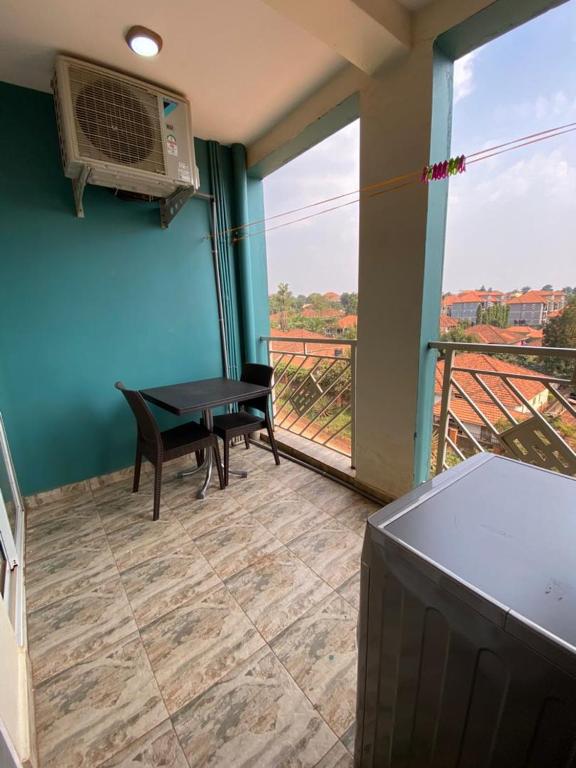 um quarto com uma mesa e uma varanda com uma ventoinha em Peacock unit30 em Kampala