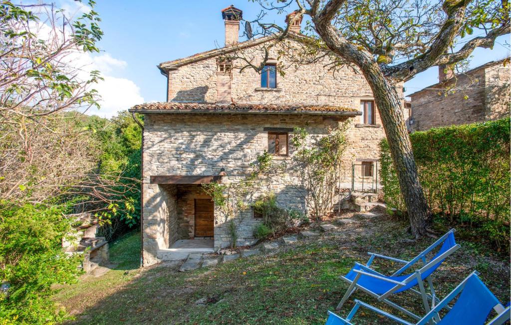 une ancienne maison en pierre avec des chaises bleues devant elle dans l'établissement Cafranceschino, à Mercatello sul Metauro