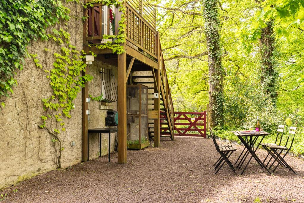 eine Terrasse mit einer Treppe, einem Tisch und Stühlen in der Unterkunft Les Gîtes du Robelier - Le nid in Bouaye