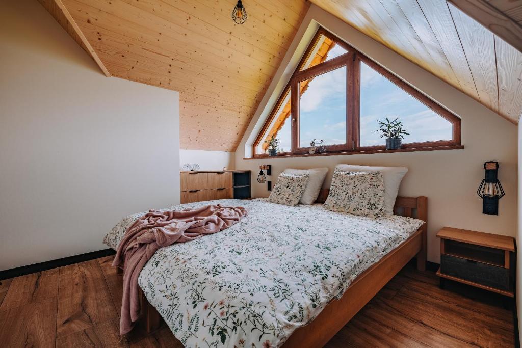 a bedroom with a bed with a large window at Domek Bajkowy Widok in Maniowy
