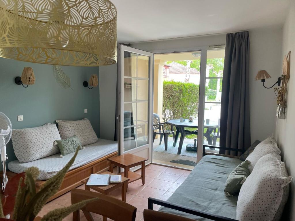 ein Wohnzimmer mit einem Sofa und einem Tisch in der Unterkunft Charmant T2 chambre lit double dans résidence du Lac in Monflanquin