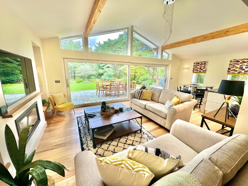 a living room with couches and a table at Luxury Five Bed Home - Large Garden with BBQ - New Forest and Beach Links in Saint Leonards