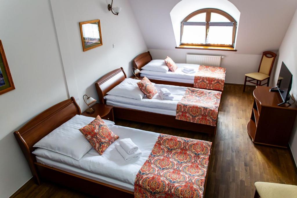 a small room with two beds and a chair at NOVA.Galicja in Nowy Sącz