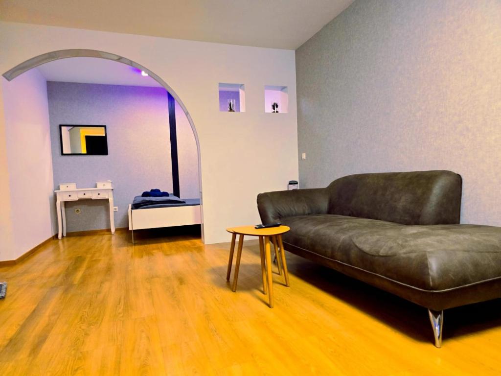 een woonkamer met een leren bank en een tafel bij B&R apartment türkischen Konsulats in Neurenberg