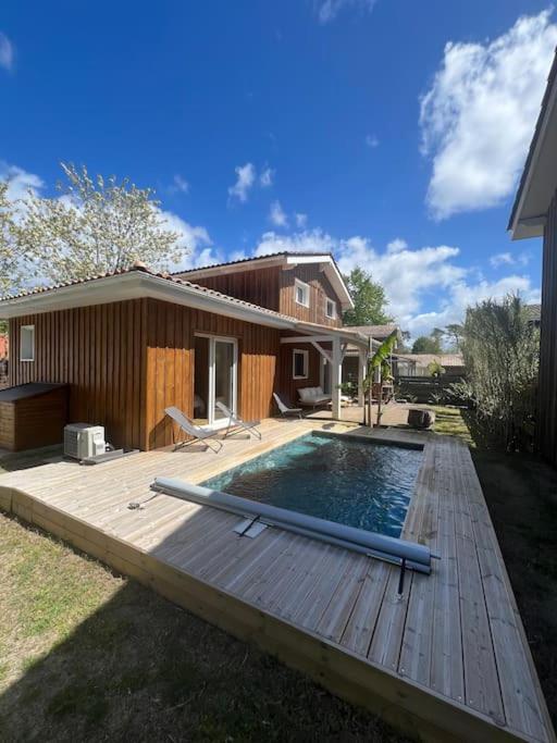 - une piscine sur une terrasse en bois à côté d'une maison dans l'établissement Villa avec piscine proche du lac, à La Teste-de-Buch