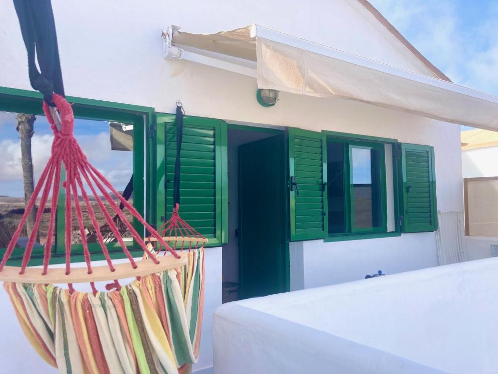 una casa con ventanas con contraventanas verdes y una hamaca en Apartamento El Islote direct at Paradise Beach, en Cotillo