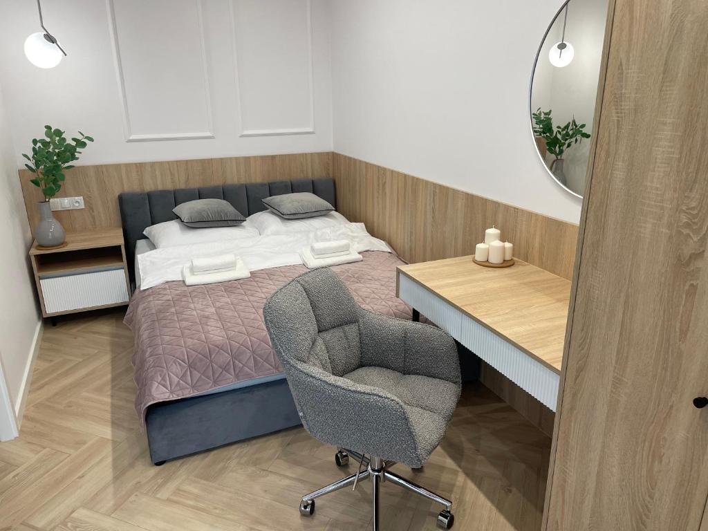 a bedroom with a bed with a desk and a chair at Imperial Citi Apartament in Kraków