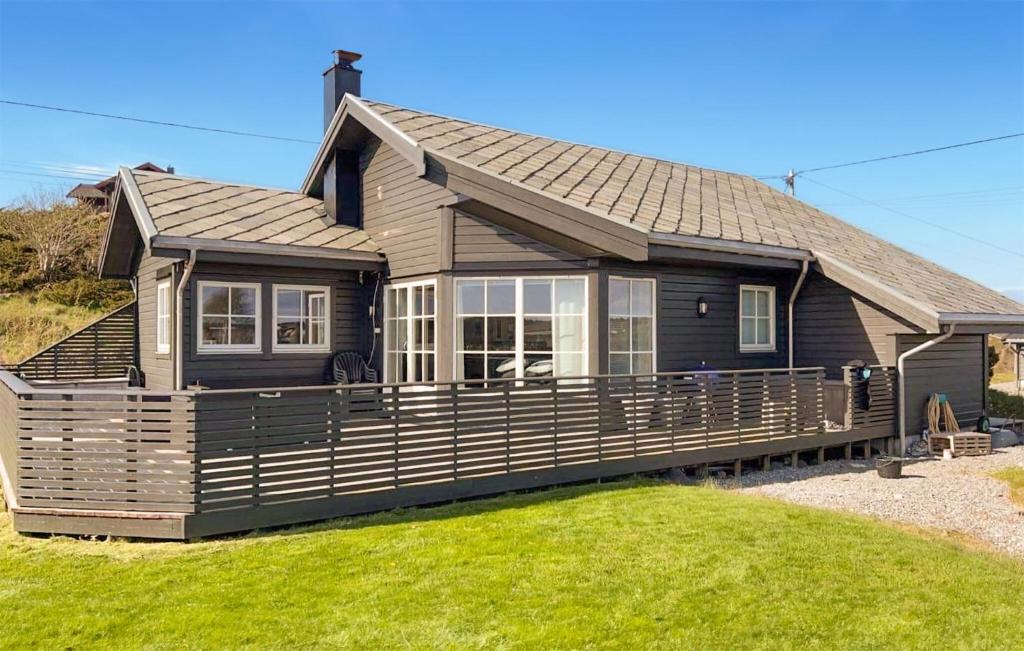 a small house with a large porch on a lawn at Stunning Home In Bvgen With House Sea View in Bøvågen