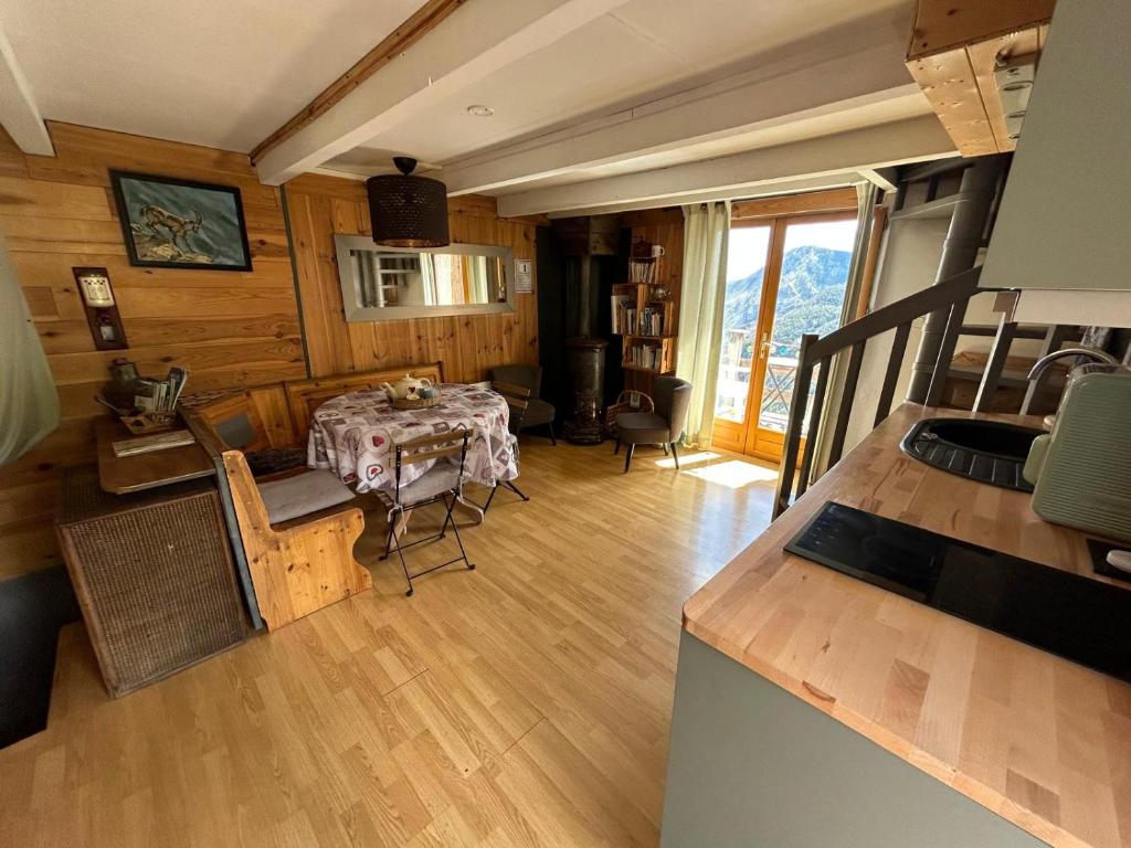 a living room with a table and a kitchen at Les 3 Flocons Roure in Roure