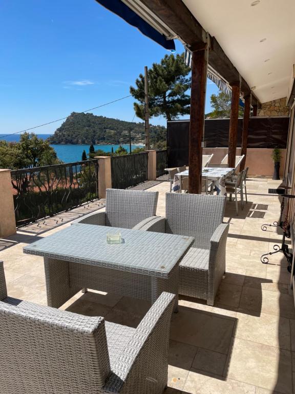 una mesa y sillas en un patio con vistas al agua en Résidence Le Golfe Bleu, en Rayol-Canadel-sur-Mer