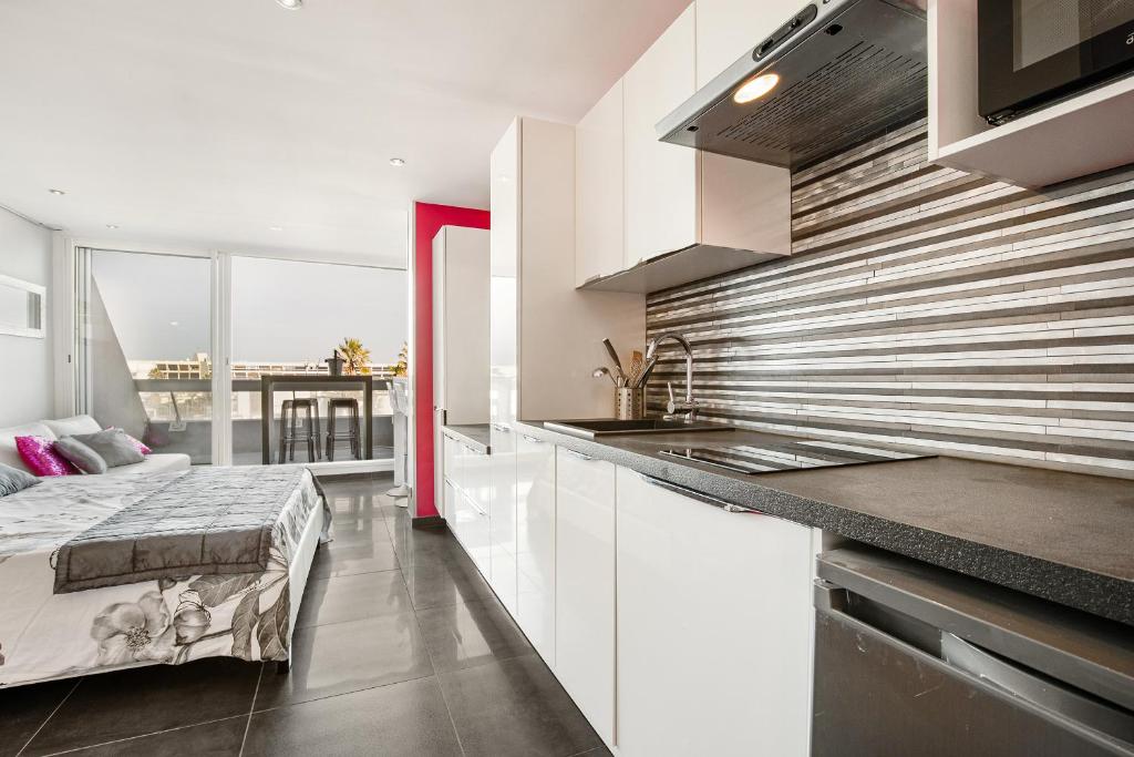 une cuisine avec des armoires blanches et un lit dans une chambre dans l'établissement Full Moon Heliopolis, au Cap d'Agde