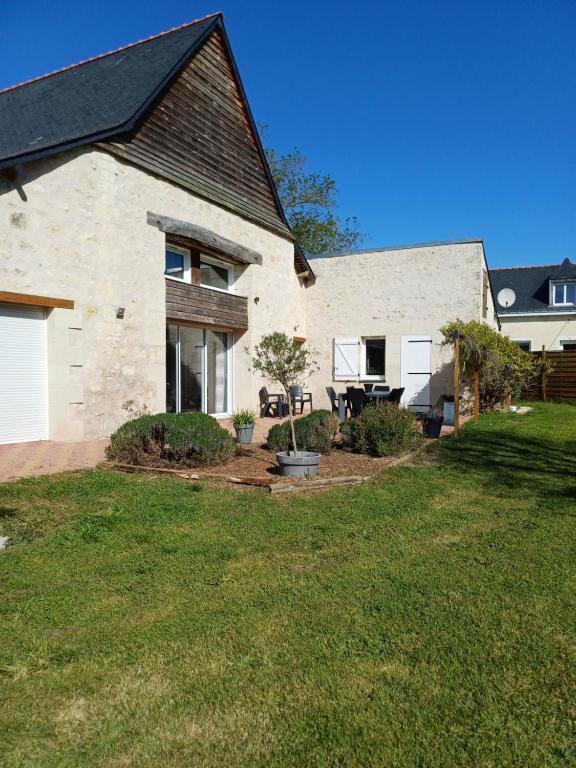 uma casa de tijolos brancos com um pátio e um quintal em La Grange des Roisnes em Longué