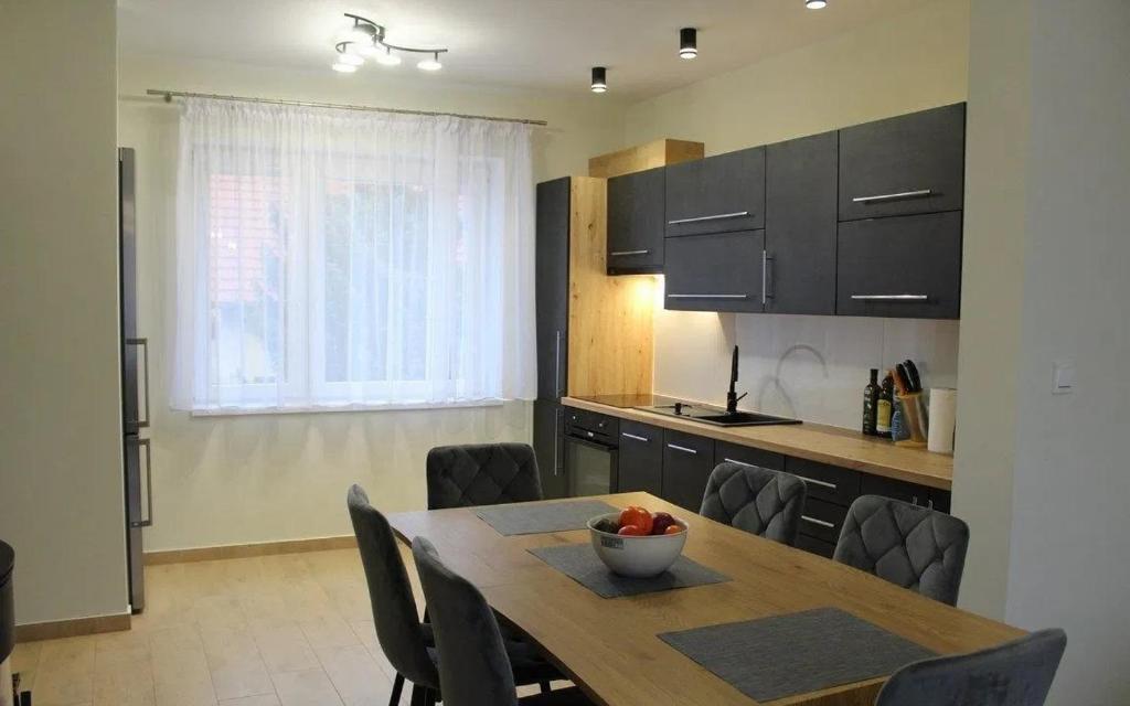 a kitchen with a wooden table and chairs and a dining room at Apartament u Jędrusia in Żywiec
