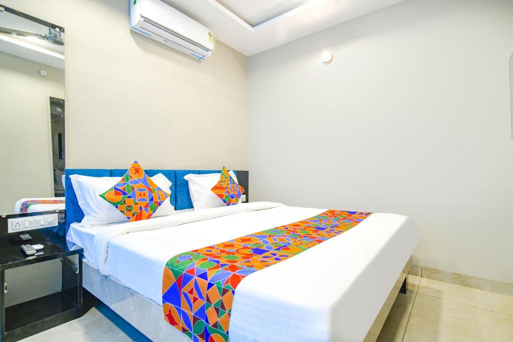 1 dormitorio con 1 cama grande y almohadas coloridas en FabHotel Lake View III, en Indore