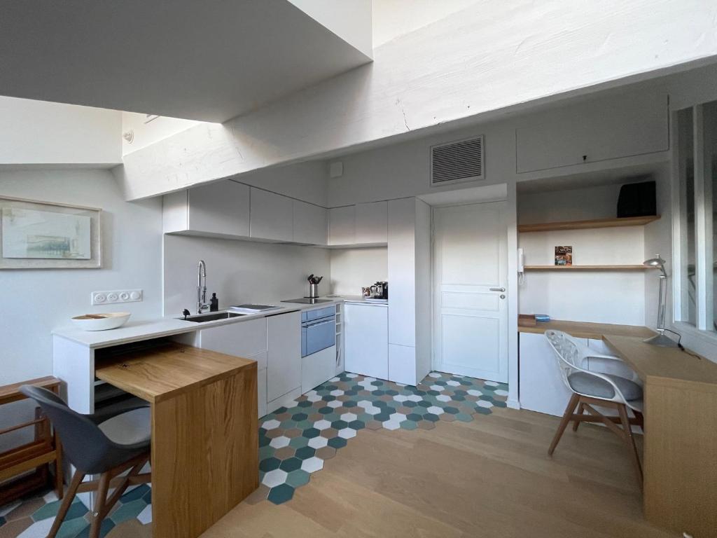 une cuisine avec des armoires blanches et une table et des chaises dans l'établissement L'Ecrin des Arts - Appt climatisé, à Toulouse