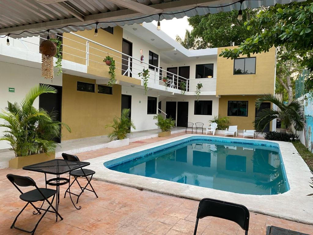 una piscina frente a una casa con sillas y mesa en Apartamentos Luna Turquesa Bacalar - Gratis Renta Bicicletas, en Bacalar