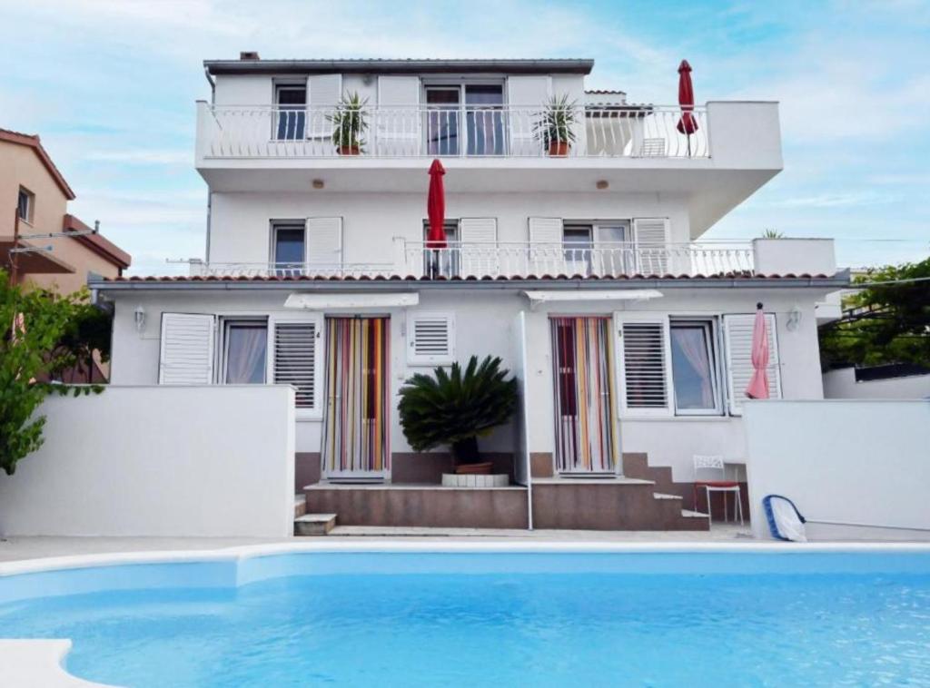 a house with a swimming pool in front of a building at Apartments Mihovilovic - 50 m from beach in Slatine