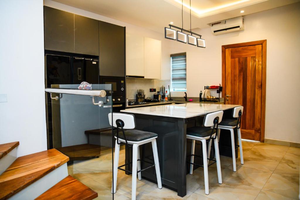 a kitchen with a black island with bar stools at Elim Maisonette in Lekki