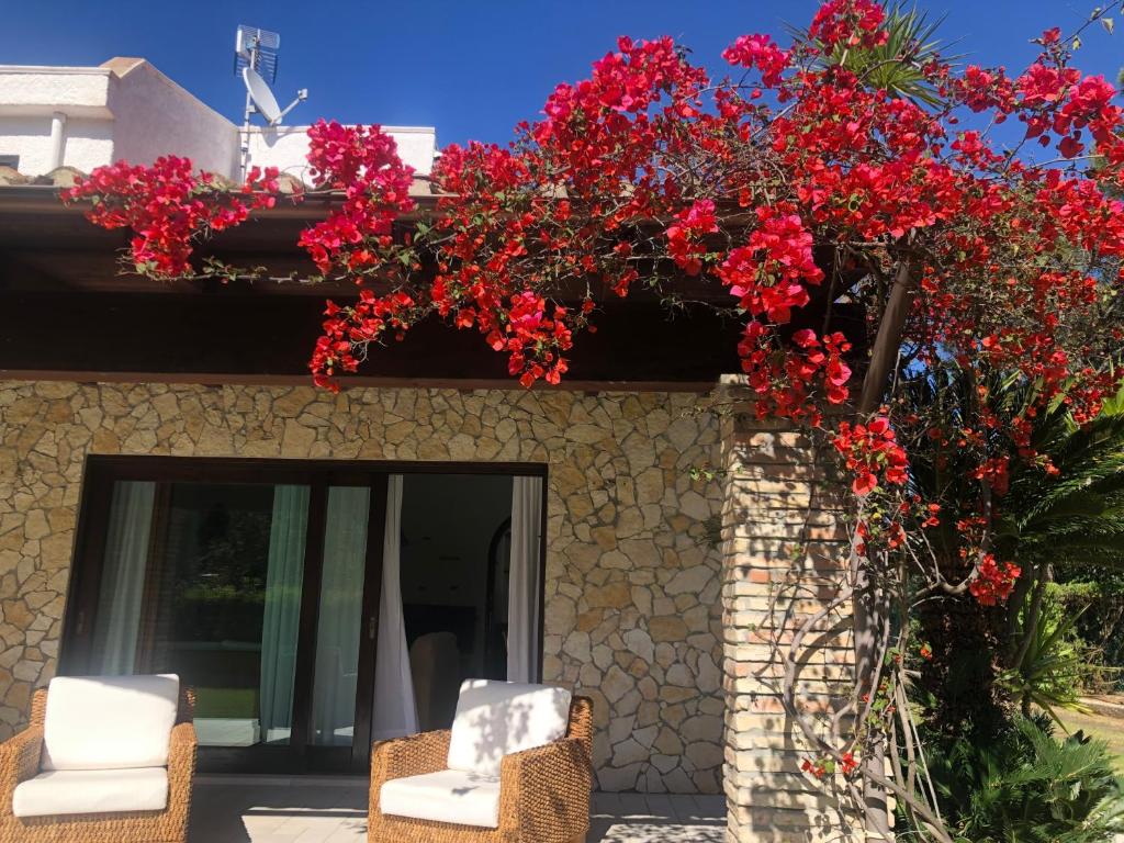 Deux chaises et des fleurs rouges sur un bâtiment dans l'établissement Villa Margherita, à Santa Margherita di Pula