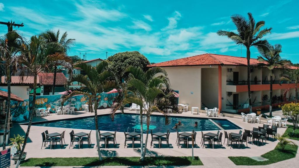 una piscina en un complejo con sillas y palmeras en Hotel Fênix, en Porto Seguro