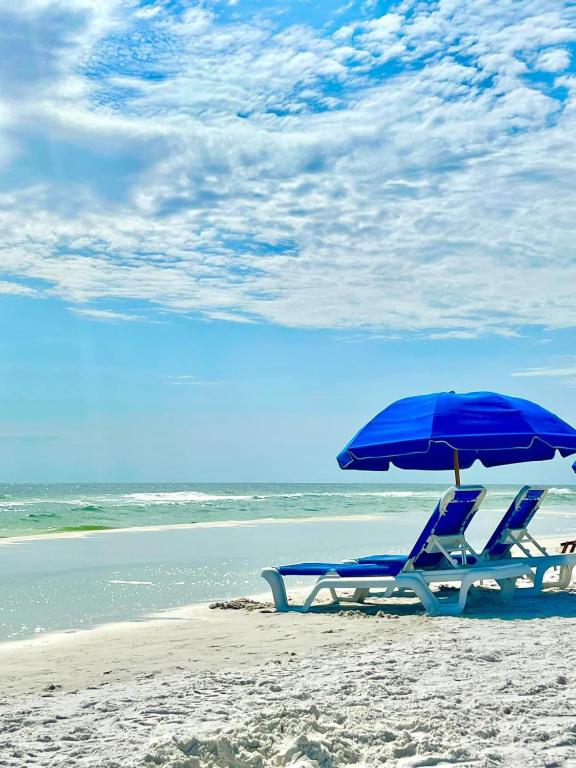 a pair of chairs and an umbrella on a beach at Beach access close to Walmart, Bowling,skating and Game room in Panama City Beach