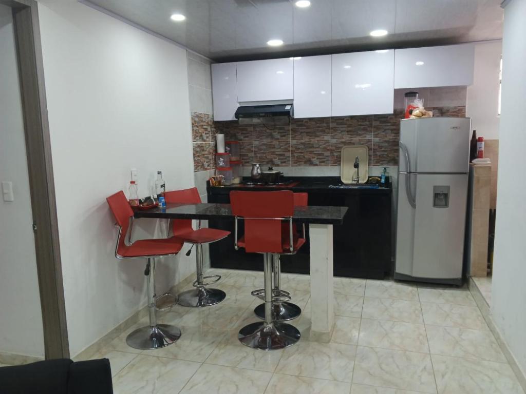 a kitchen with red chairs and a refrigerator at Tres Reyes apto in Soacha