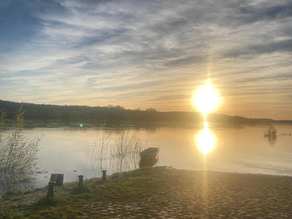 una puesta de sol sobre un lago con la puesta de sol en 100 m2 de charme vue sur la Loire, en Saint-Clément-des-Levées